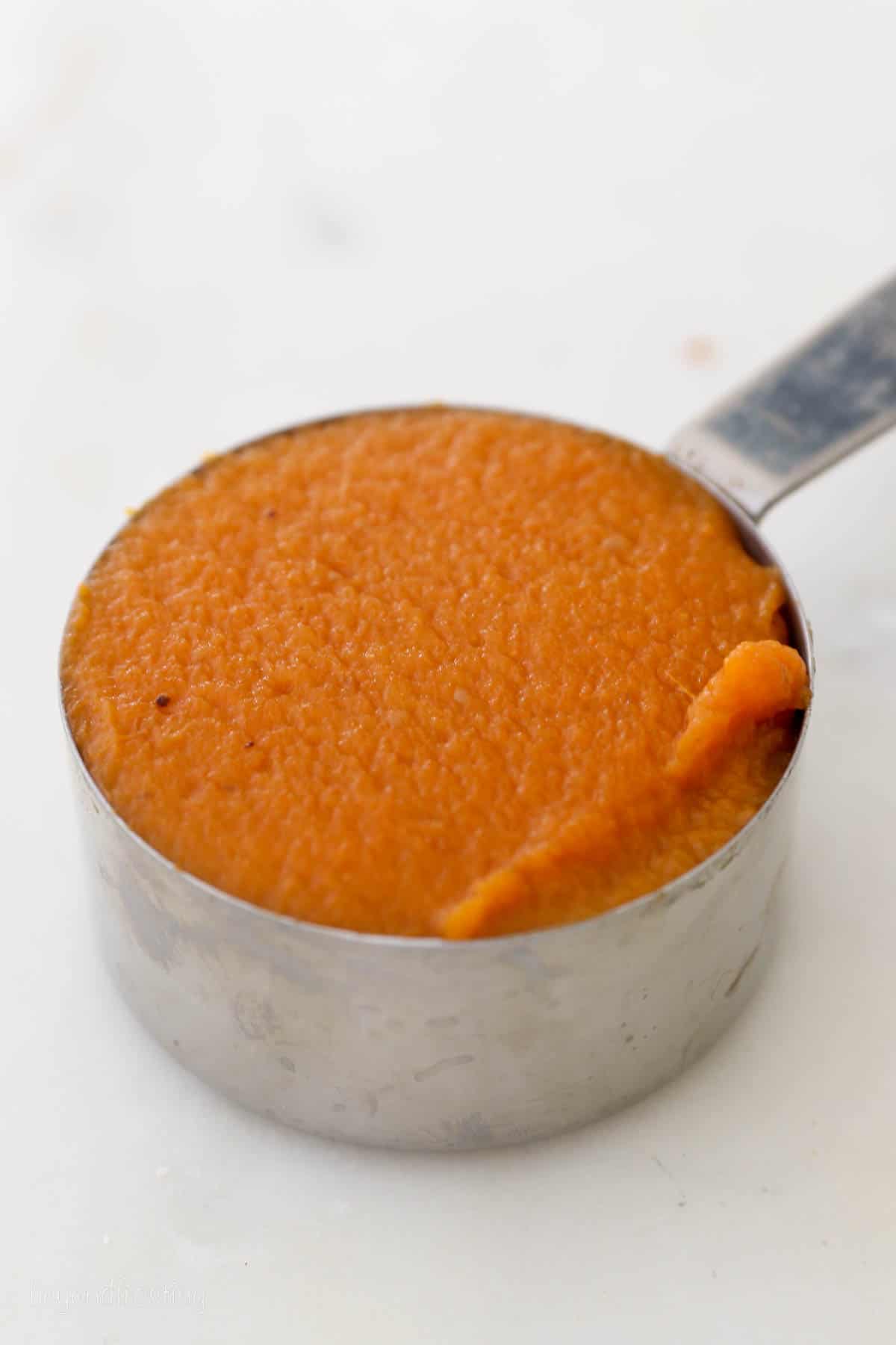 a silver measuring cup with pumpkin puree