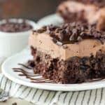 closeup of a slice of chocolate poke cake on a white plate