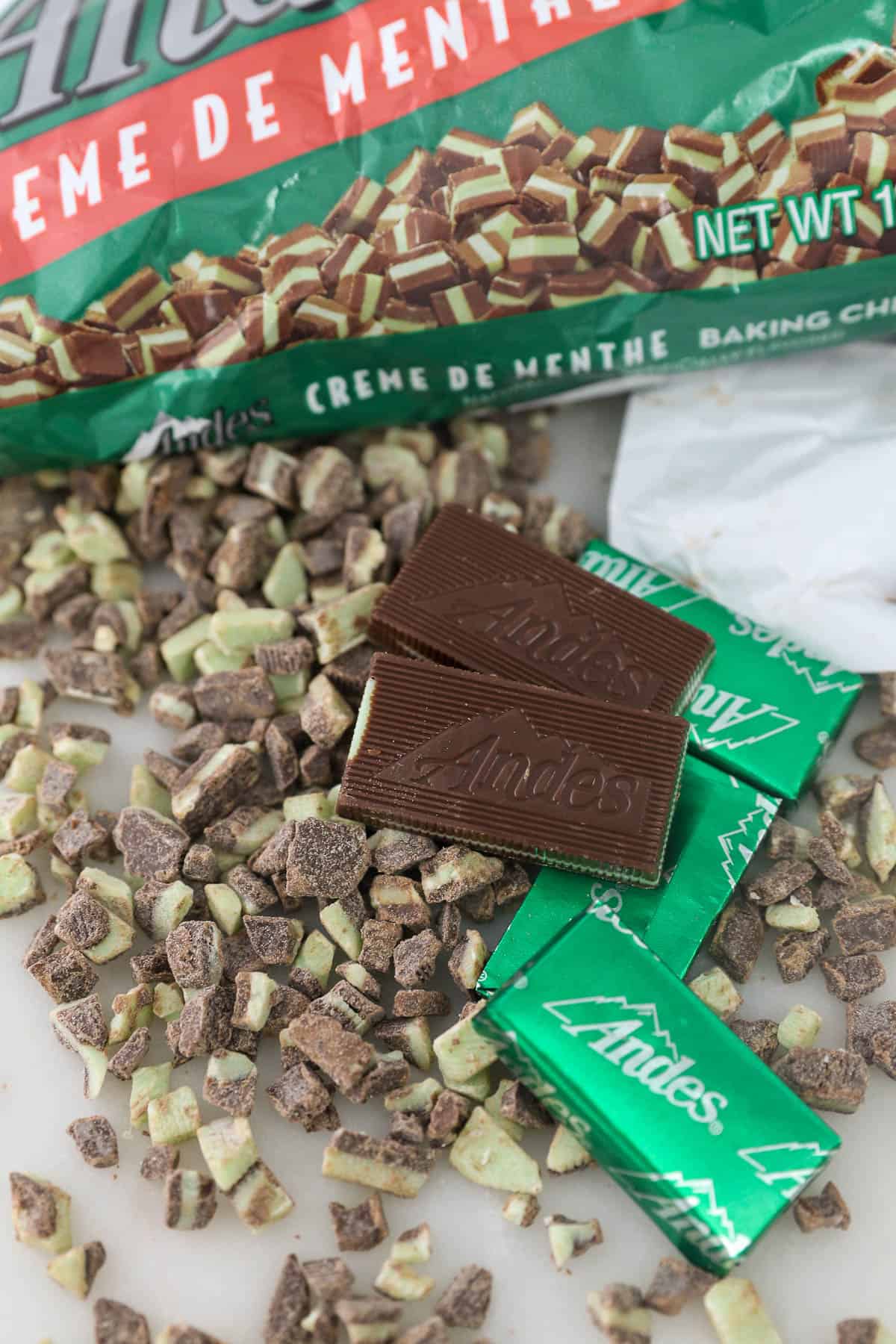 Wrapped and unwrapped Andes Mints scattered on top of chopped Andes Mint candies.