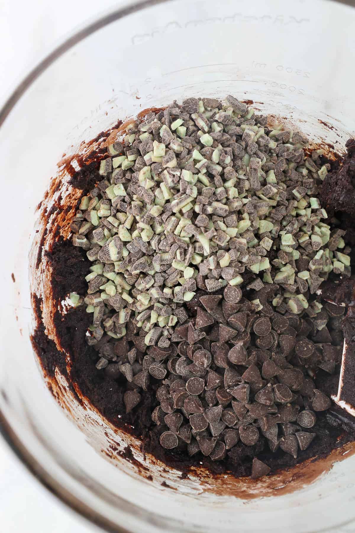 Chopped up Andes Mint candies added to chocolate cookie dough in a mixing bowl.