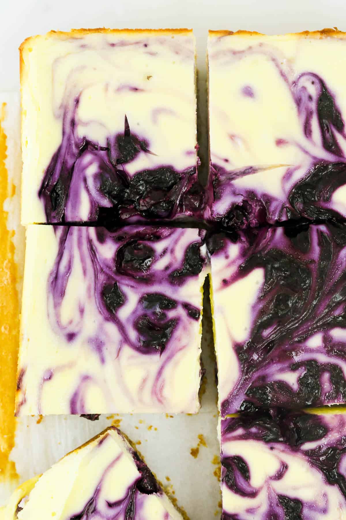 overhead photo of a blueberry swirl in some sliced cheesecake bars