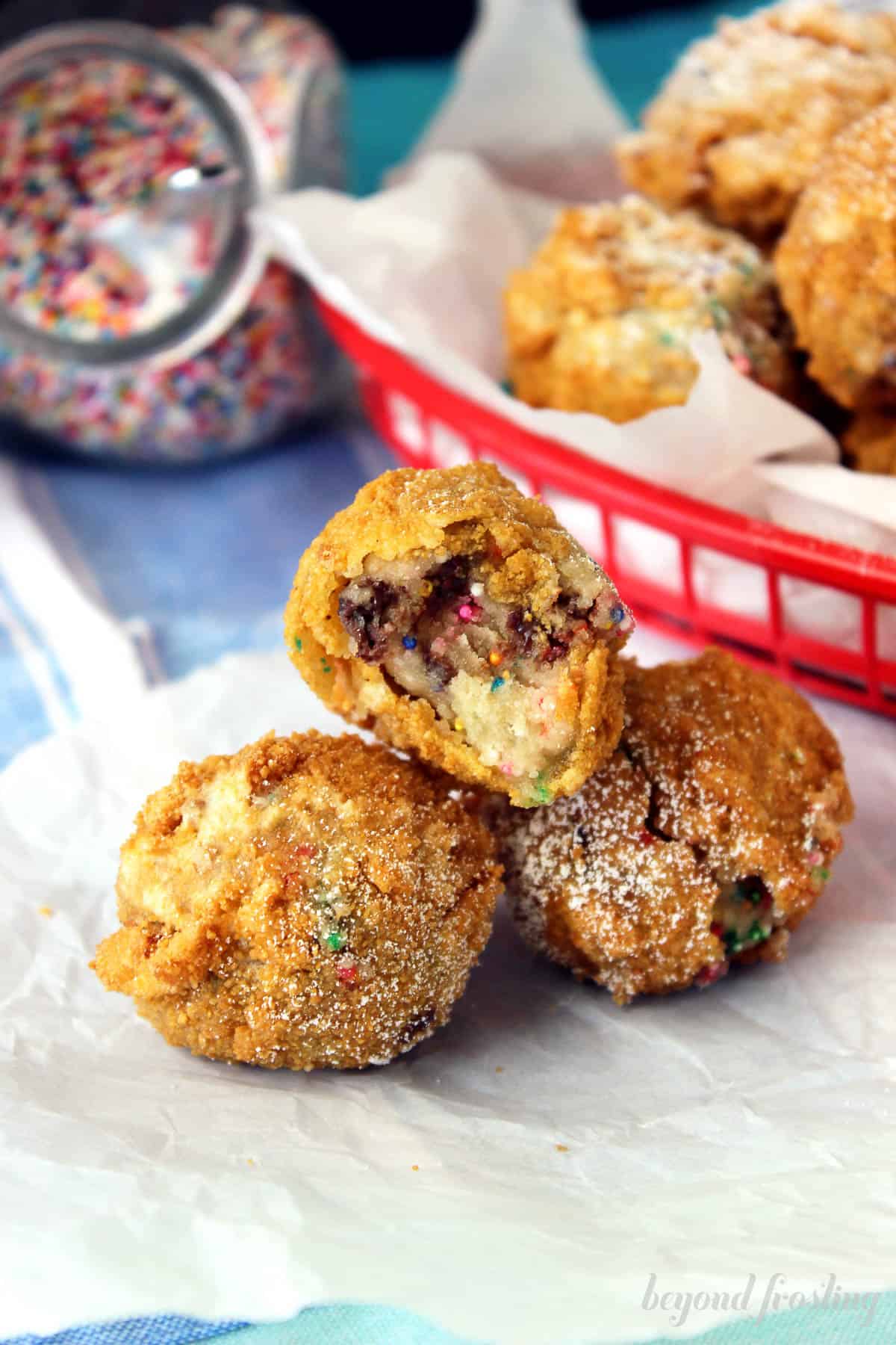 three pieces of deep fried cookie dough, stacked, one with a bite missing