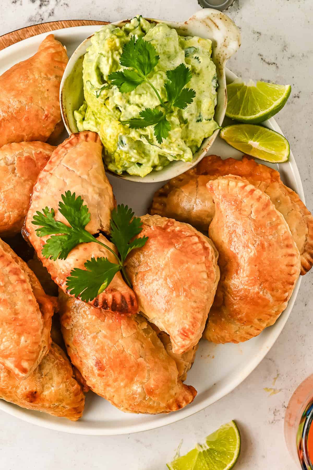 Chicken empanadas on a plate with a bowl of avocado crema for dipping.