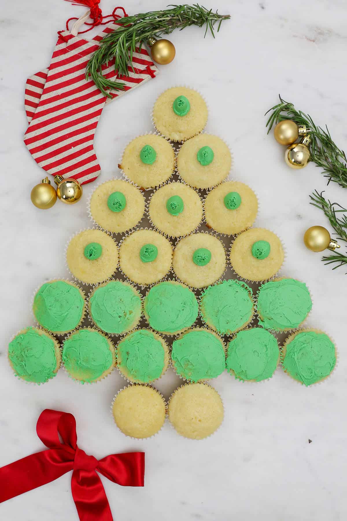 Cupcakes assembled in a Christmas tree shape with a thin layer of green buttercream spread onto eleven of them