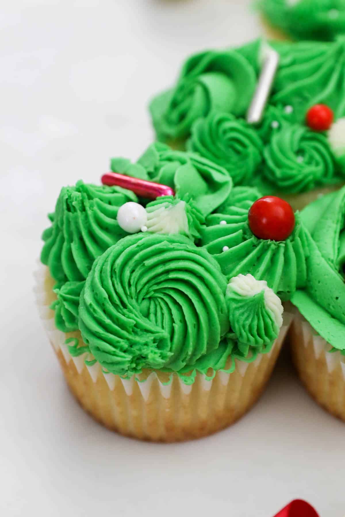 A vanilla cupcake decorated with swirls and roses made out of green frosting