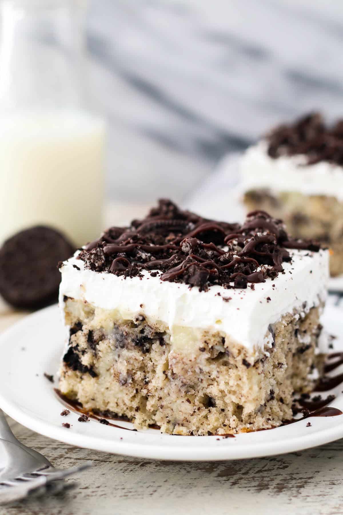 side view of a square of Oreo poke cake on a white plate.
