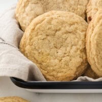 Close up of maple brown sugar cookies in a cloth-lined tin.