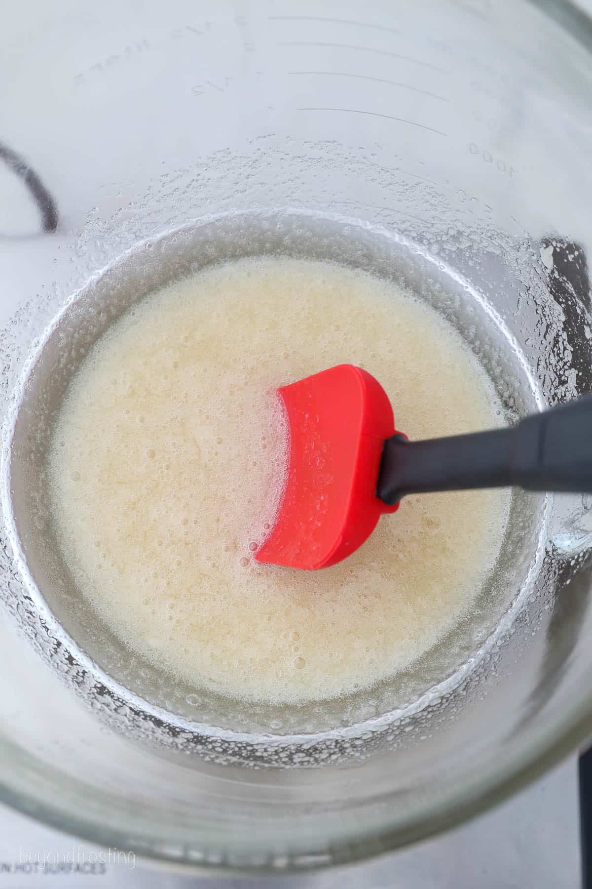 Overhead view of egg whites and sugar stirred together over a double boiler.