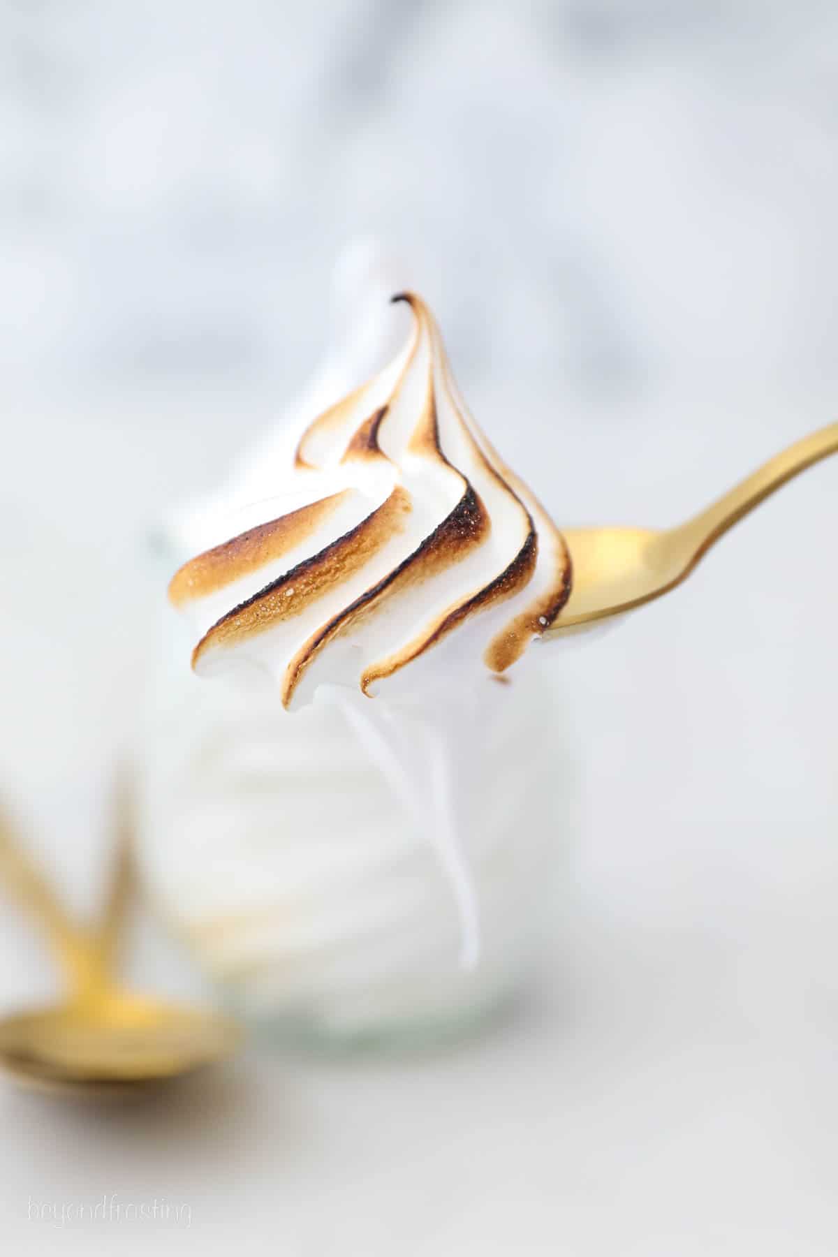Close up of a spoonful of a toasted peak of marshmallow frosting.