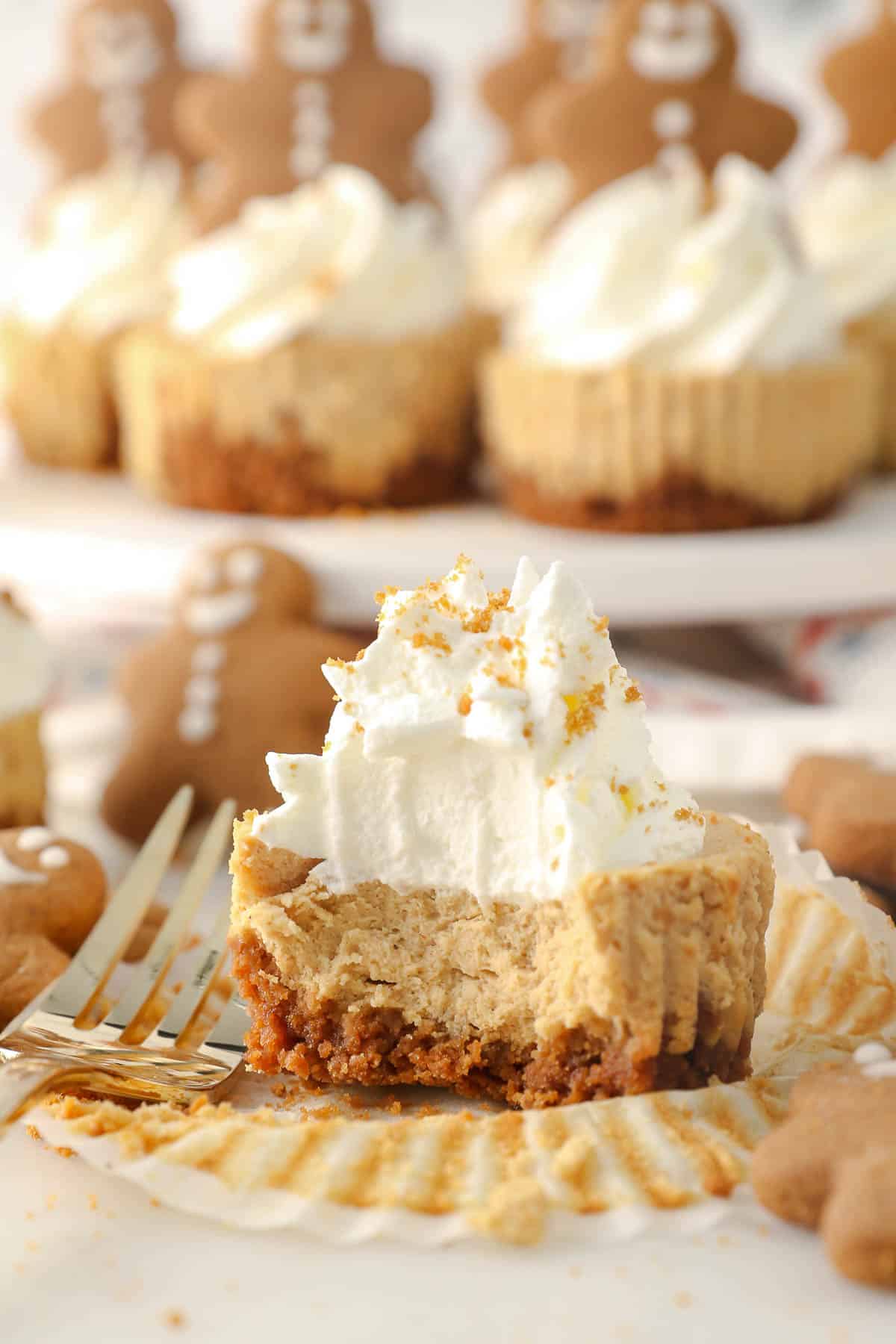 A mini gingerbread cheesecake with whipped cream with a couple bites missing