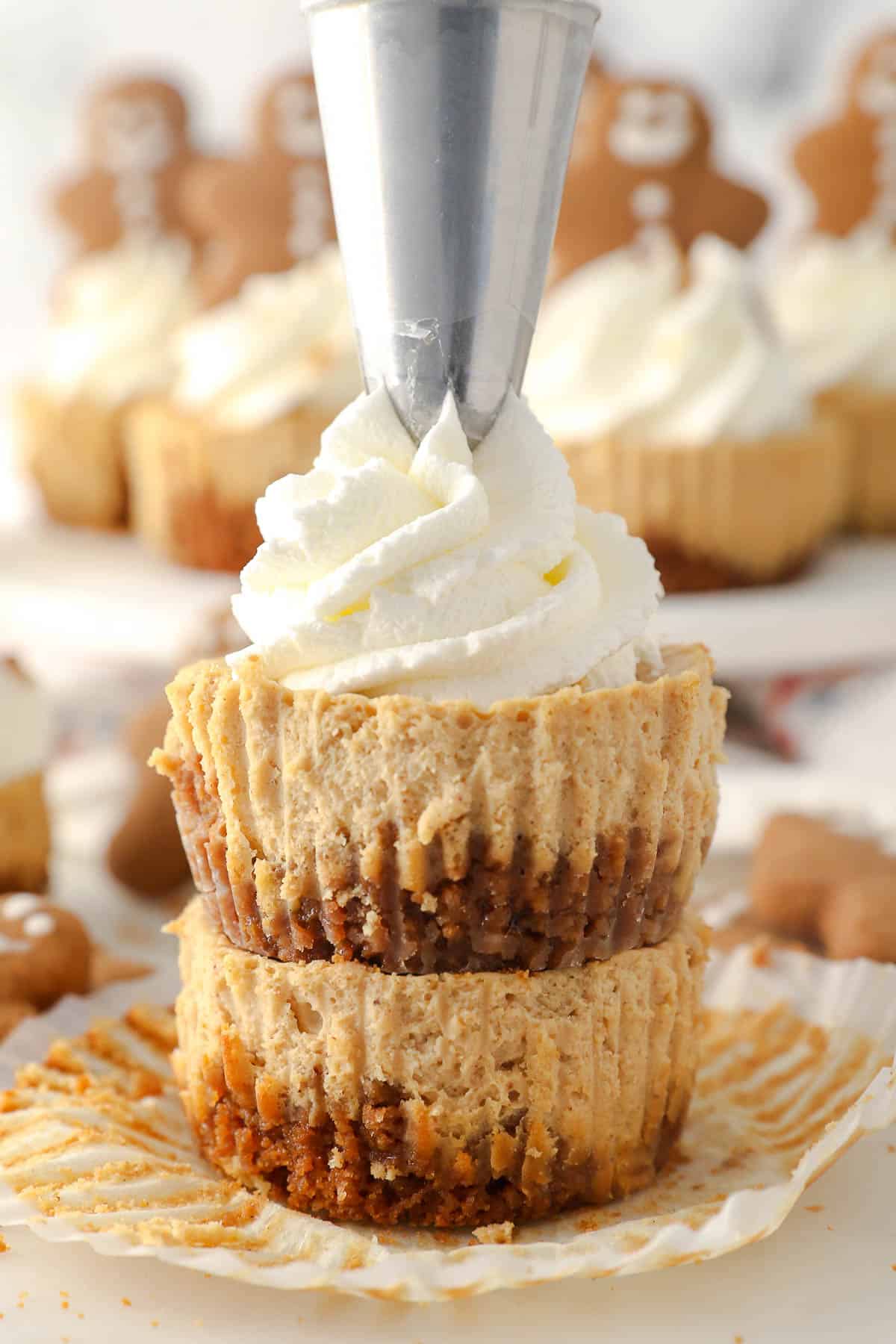 Whipped cream being piped on top of a stack of Gingerbread cheesecakes