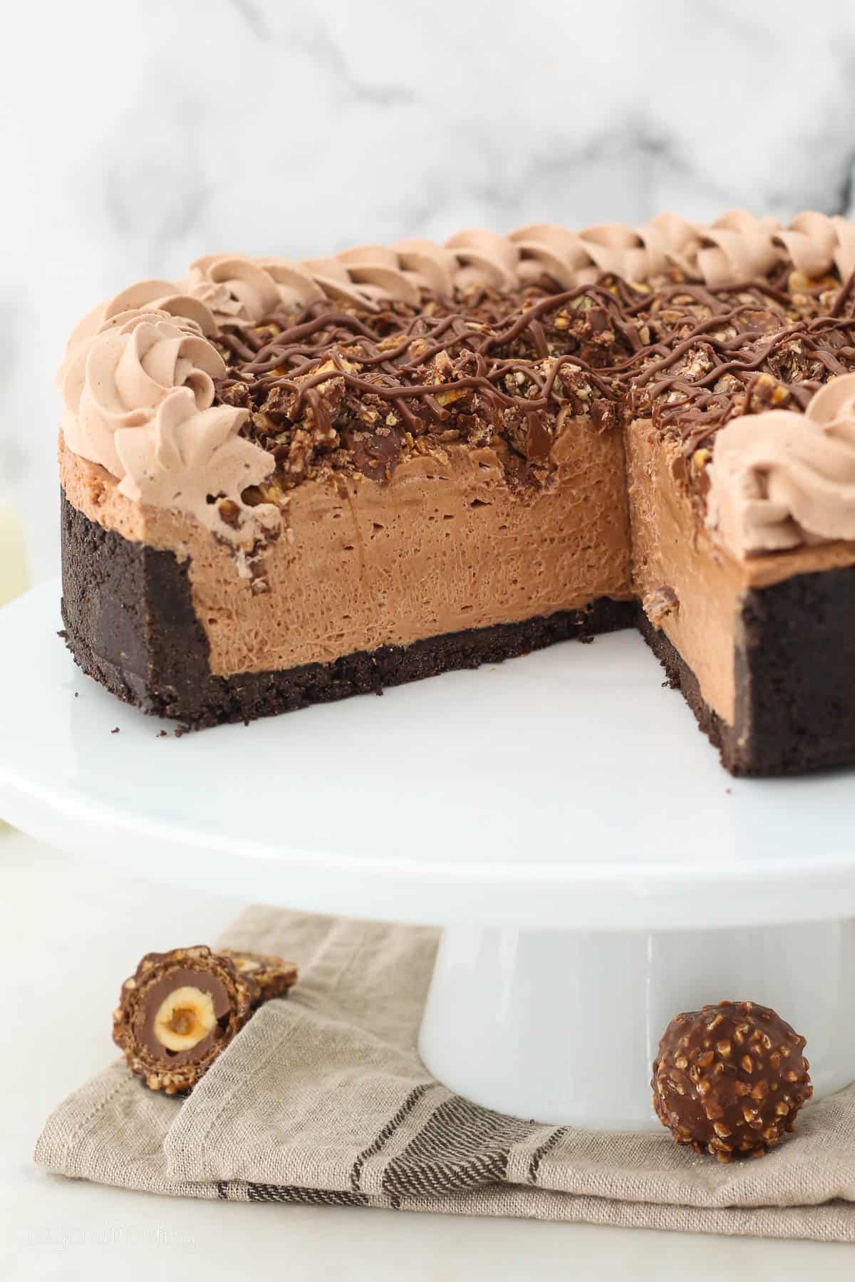 a nutella cheesecake on a cake stand with a slice cut out.