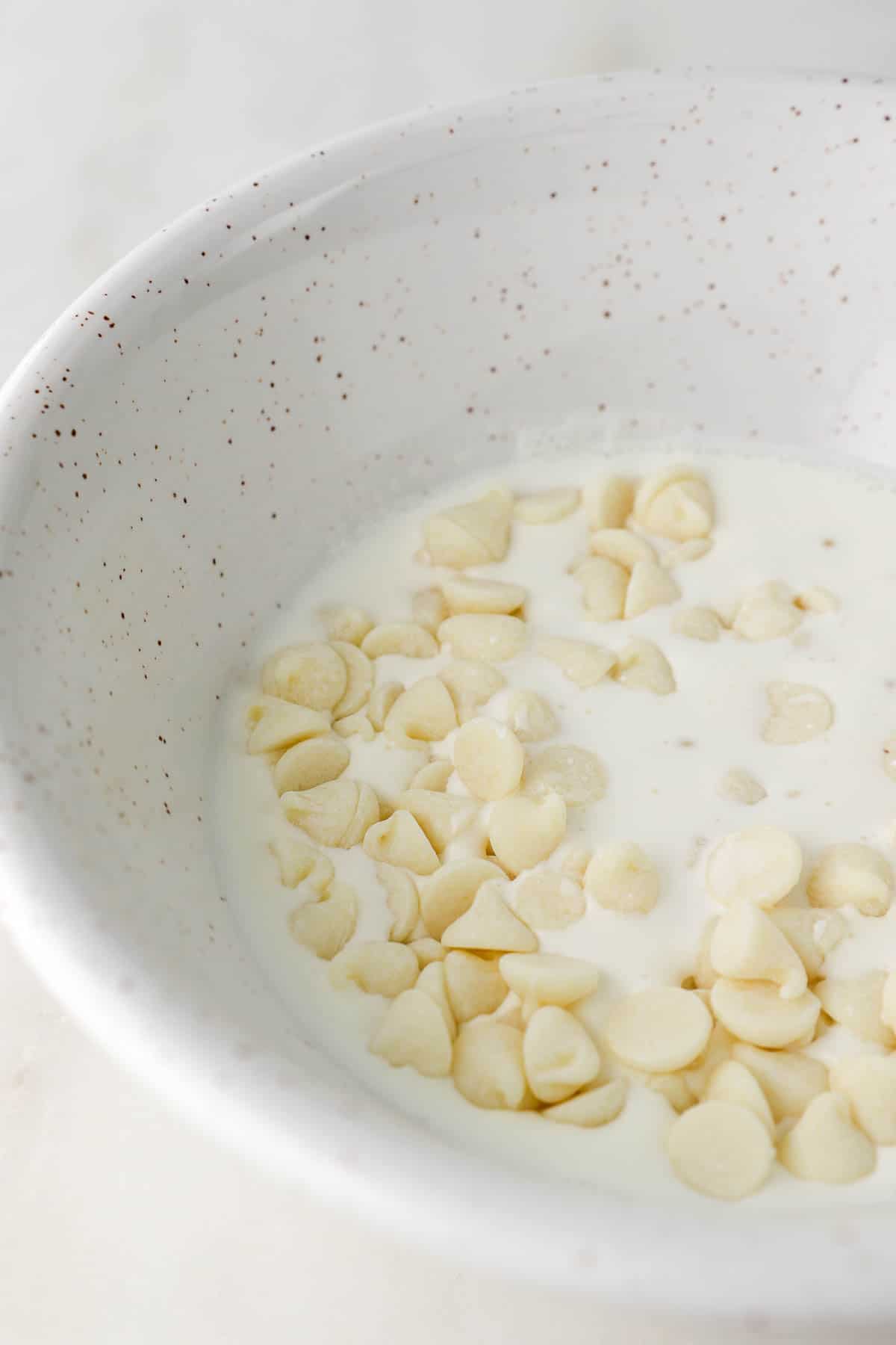 white chocolate chips in a bowl with heavy cream.