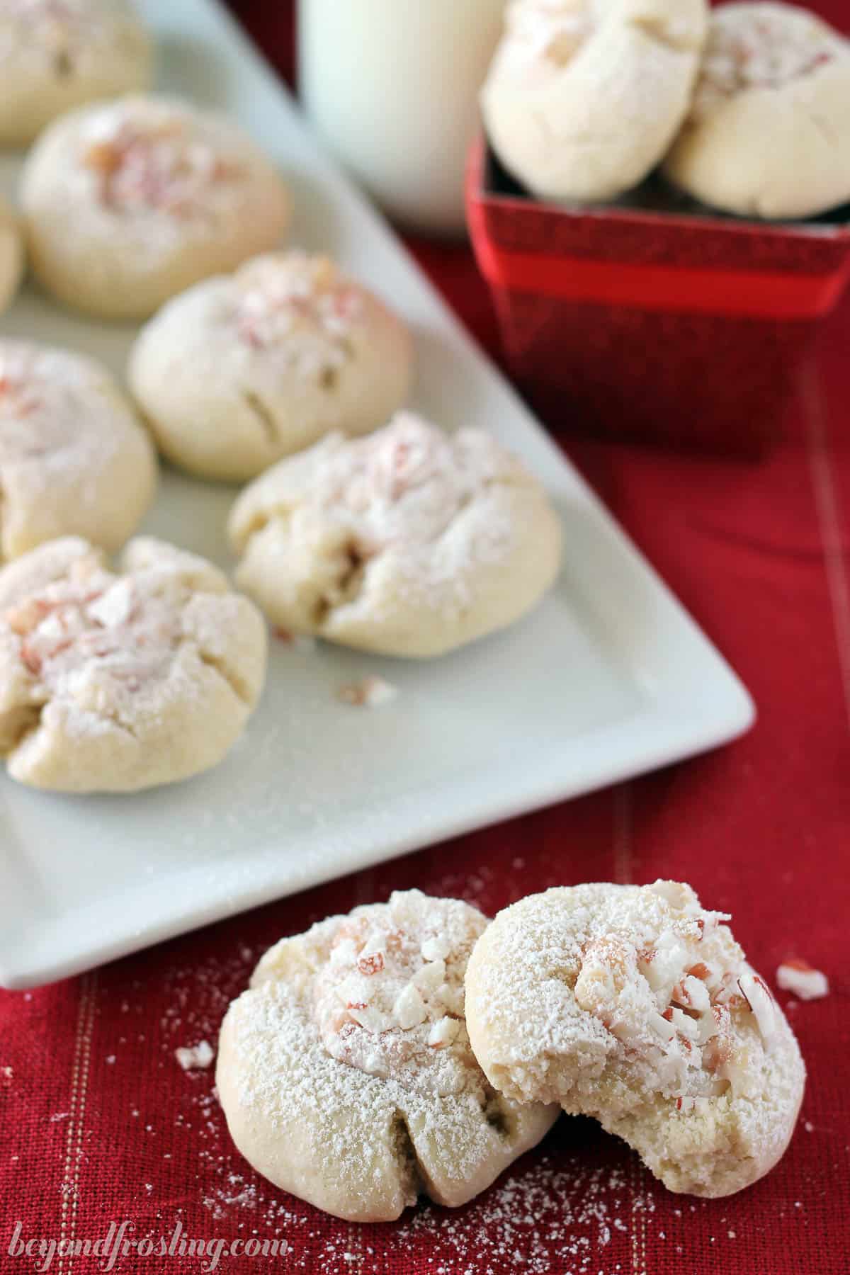 Two peppermint thumbprint cookies stacked in front of another plate of cookies
