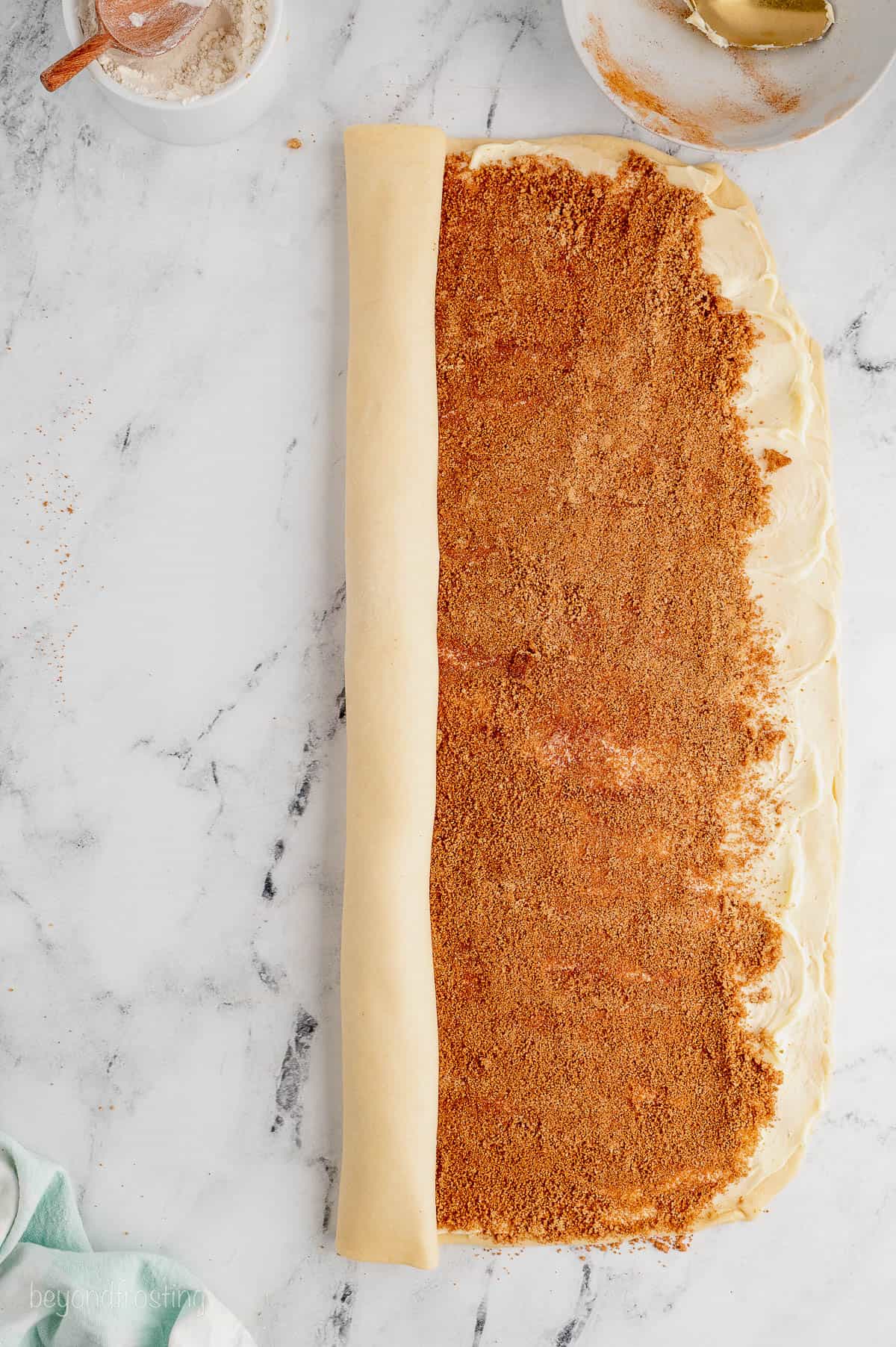 Dough filled with cinnamon sugar is rolled up lengthwise into a log.