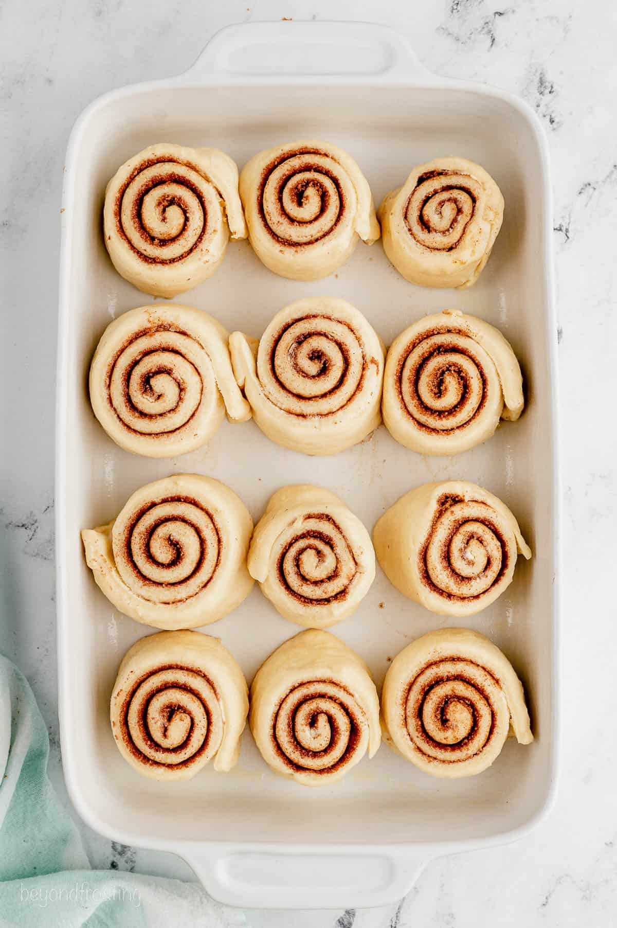Cinnamon rolls after rising in a ceramic baking dish.