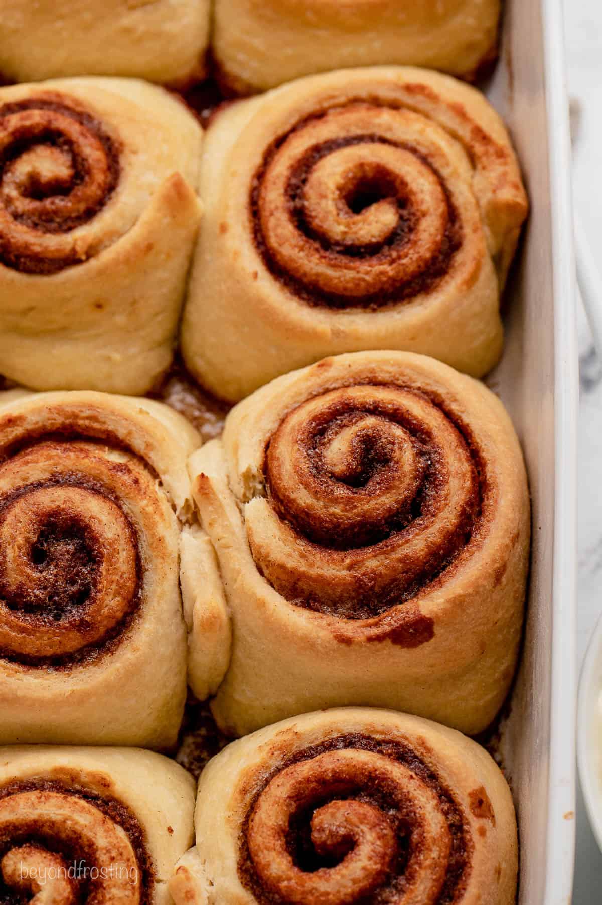 Close up of baked cinnamon rolls in a ceramic dish.