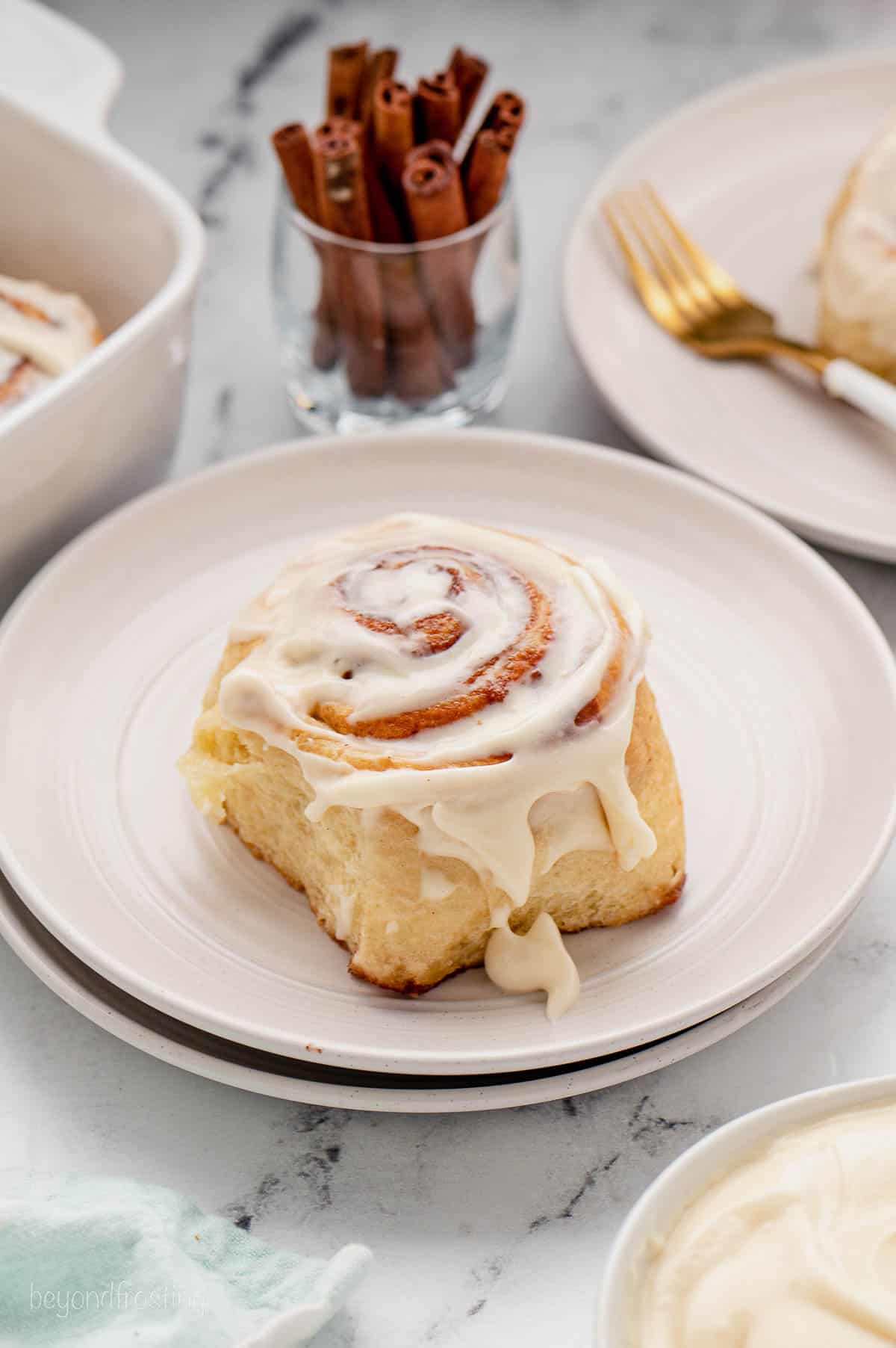 A cinnamon roll topped with cream cheese frosting on a plate.