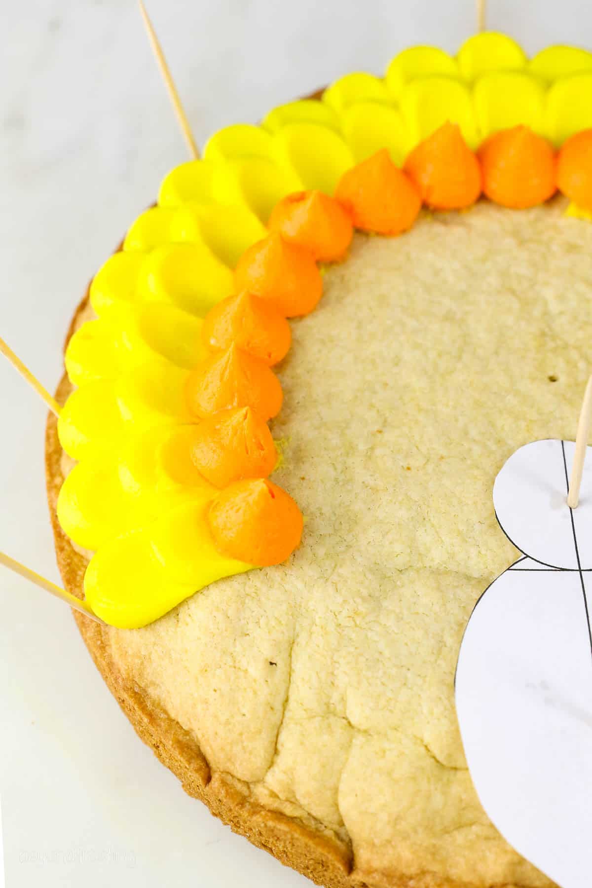 Close up of yellow and orange buttercream pedal frosting technique on a cookie cake
