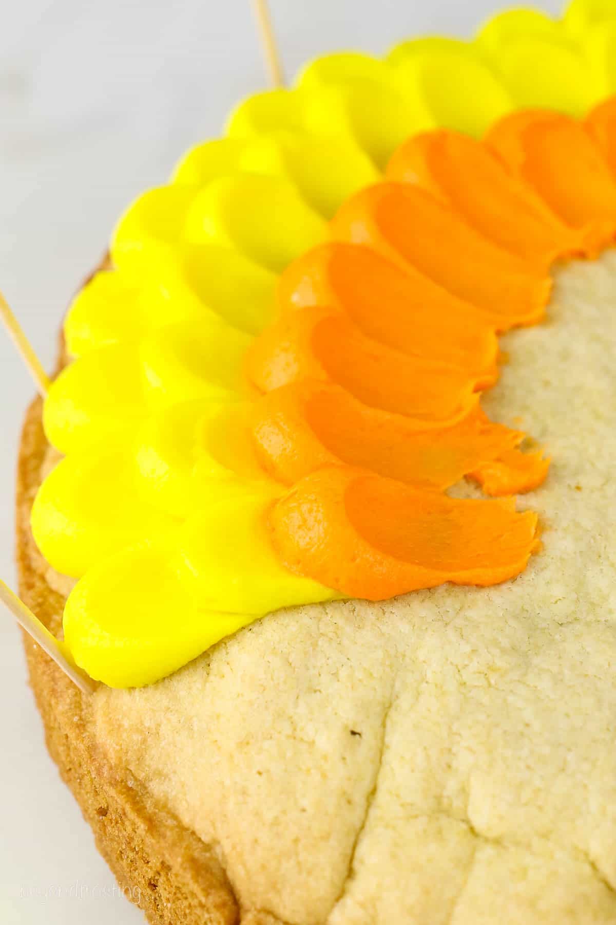Close up of yellow and orange buttercream pedal frosting technique on a cookie cake