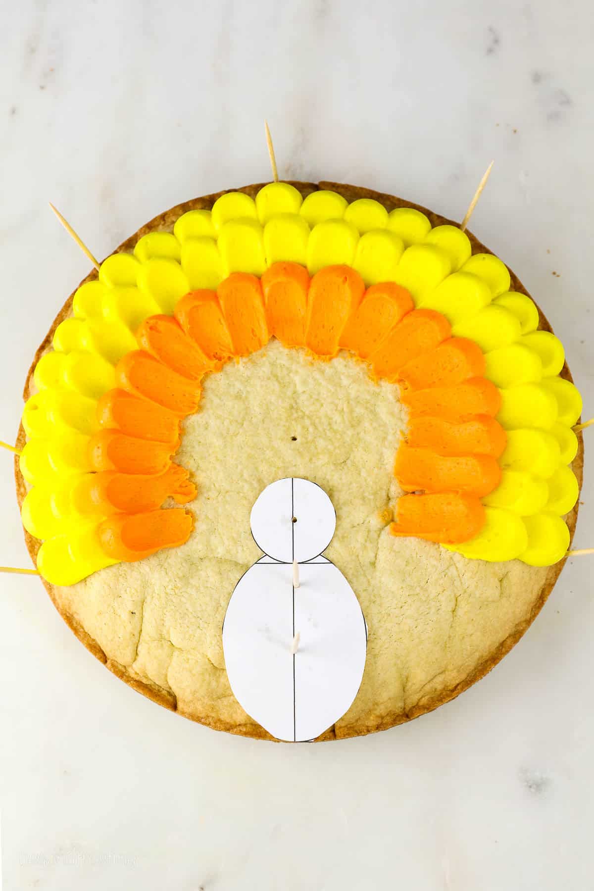 process photo of piped orange and yellow buttercream on a round cookie