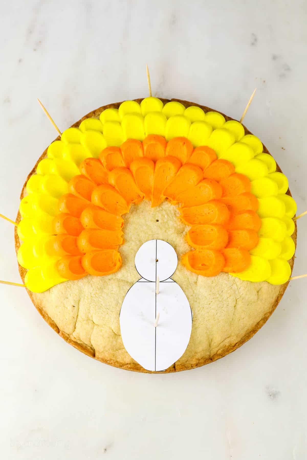 process photo of piped orange and yellow buttercream on a round cookie