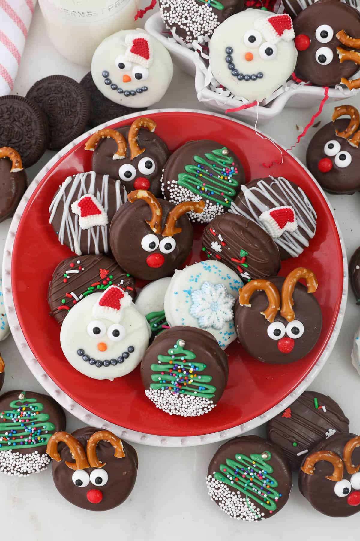 A plate filled with assorted Christmas Oreos decorated to look like reindeer, snowmen, and Christmas trees.
