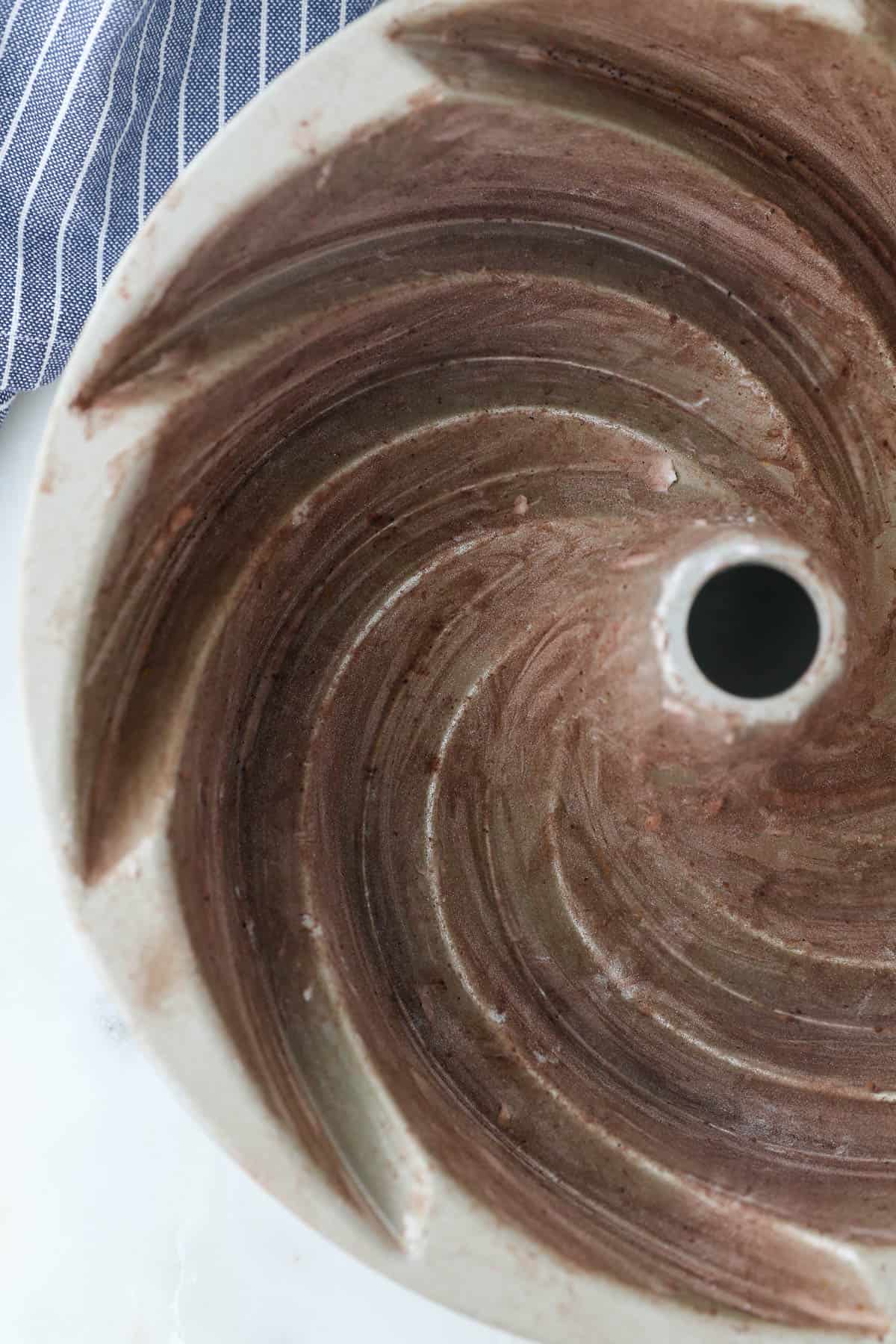 Overhead view of a greased bundt pan dusted with cocoa powder and flour.