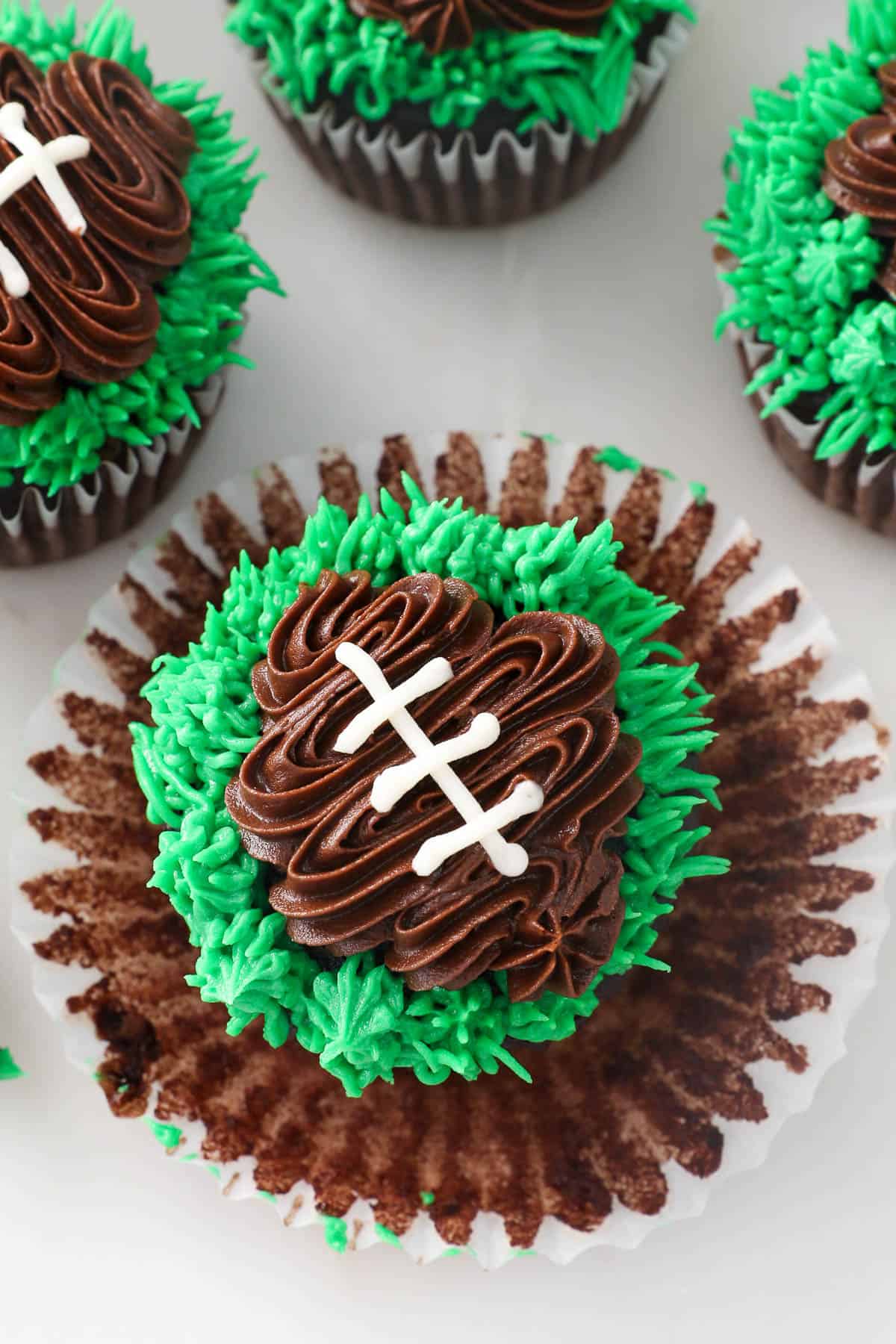 Close up overhead view of a frosted football cupcake with the cupcake liner peeled away.