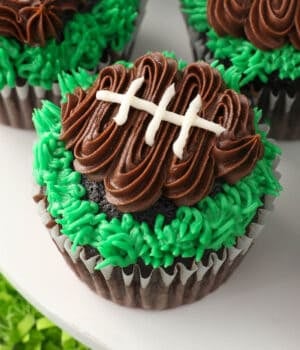 Close up of frosted football cupcakes on a cake stand.