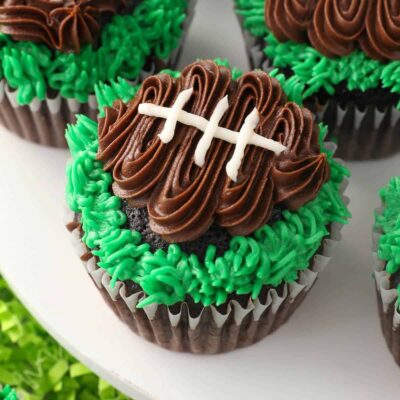 Close up of frosted football cupcakes on a cake stand.