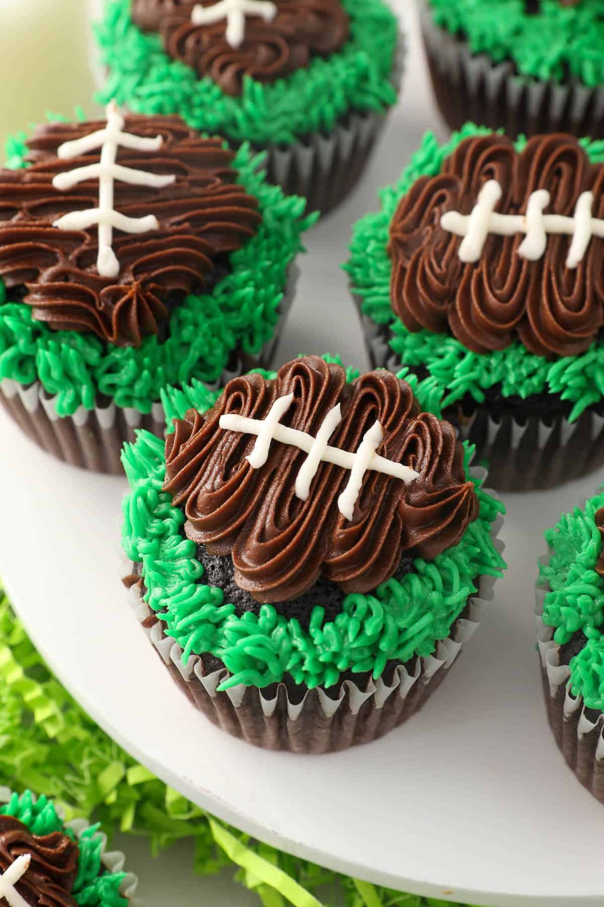 Close up of frosted football cupcakes on a cake stand.