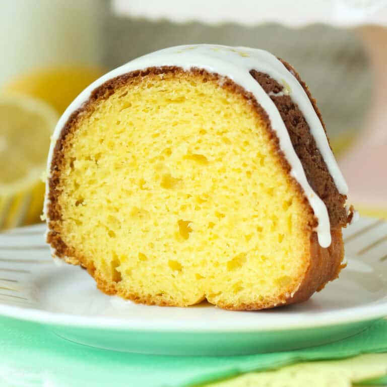 A slice of glazed lemon bundt cake on a white plate.