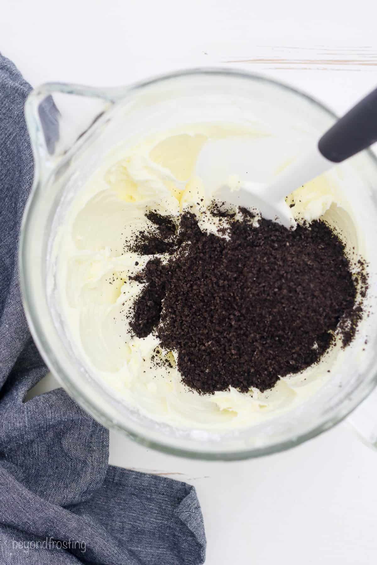 overhead of crushed Oreos being mixed into a bowl of frosting