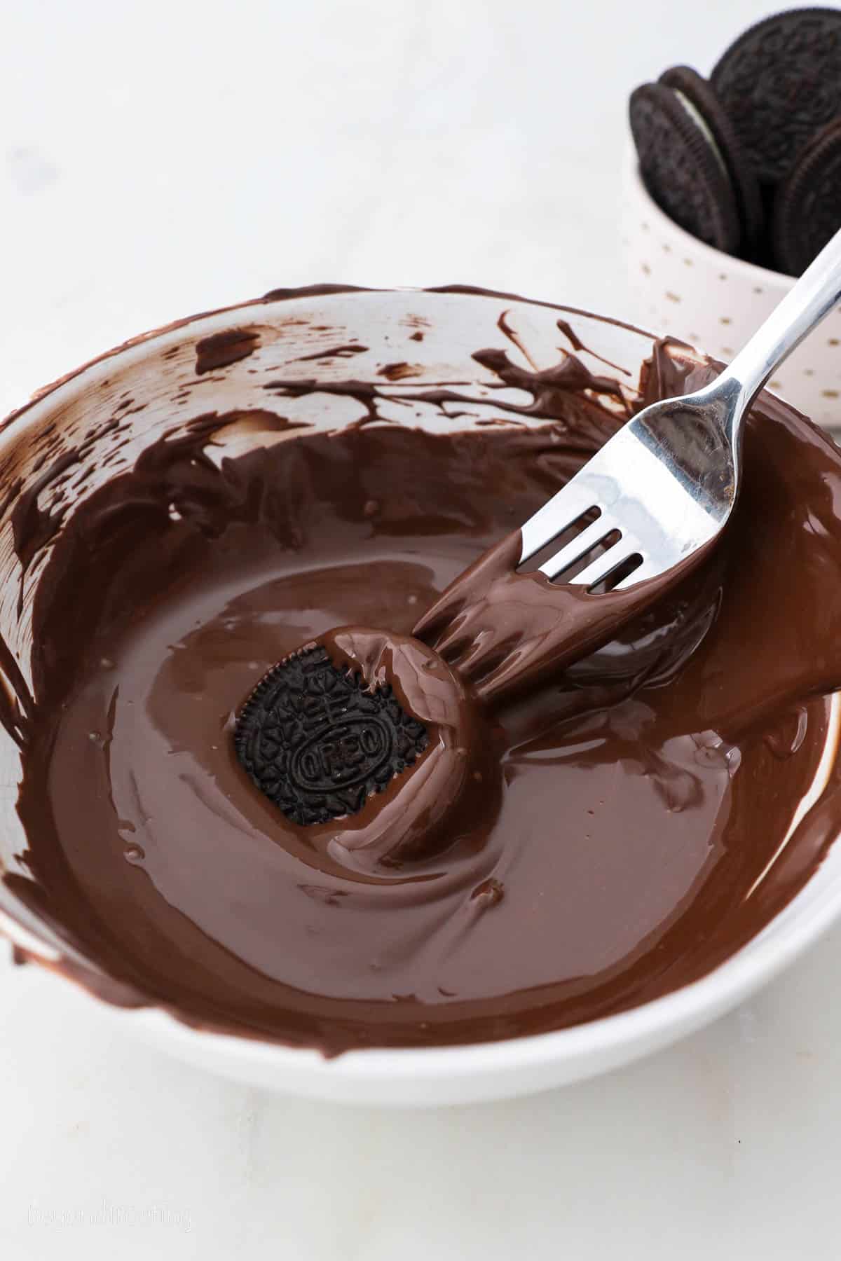 A Bowl of Melted Chocolate with an Oreo and a fork dipping in it