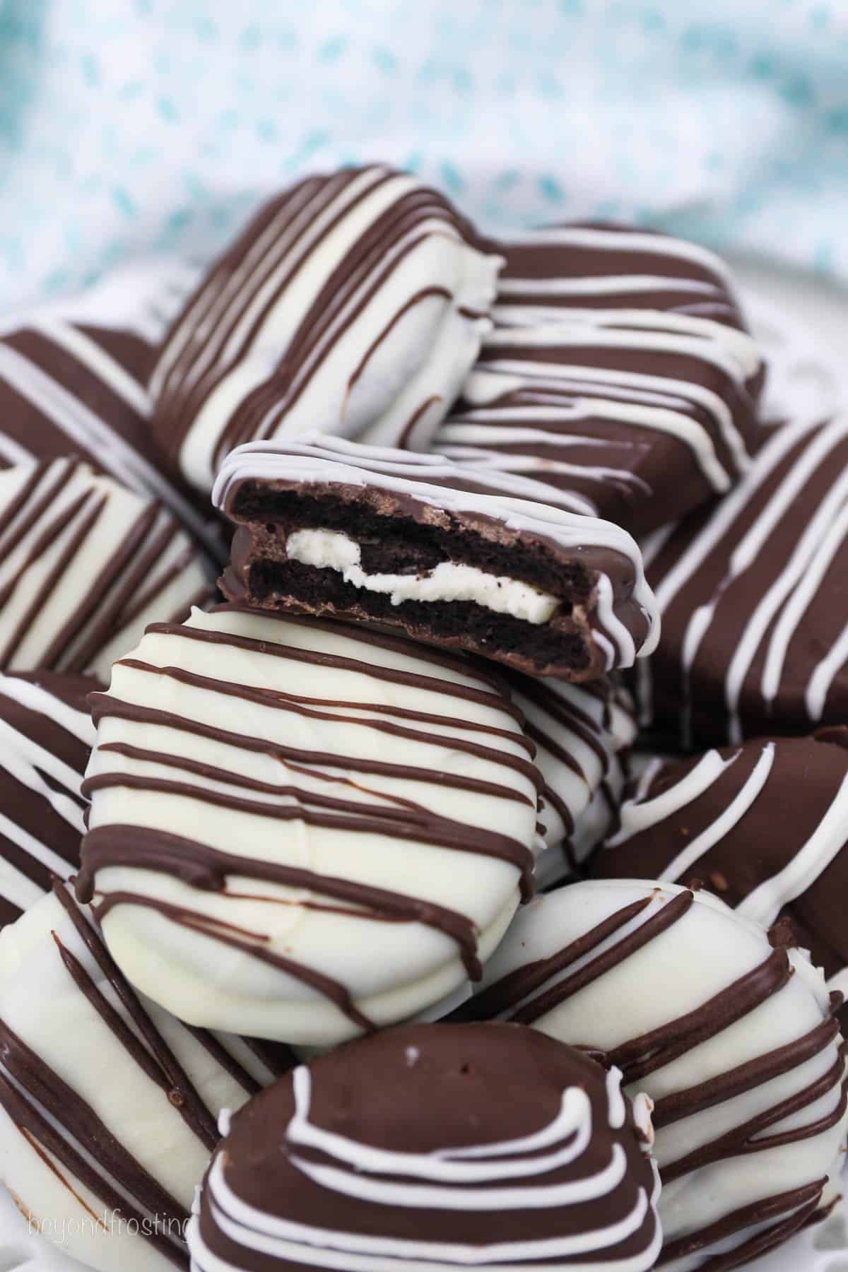 A Pile of Chocolate Covered Oreos with Chocolate Drizzle on a Plate