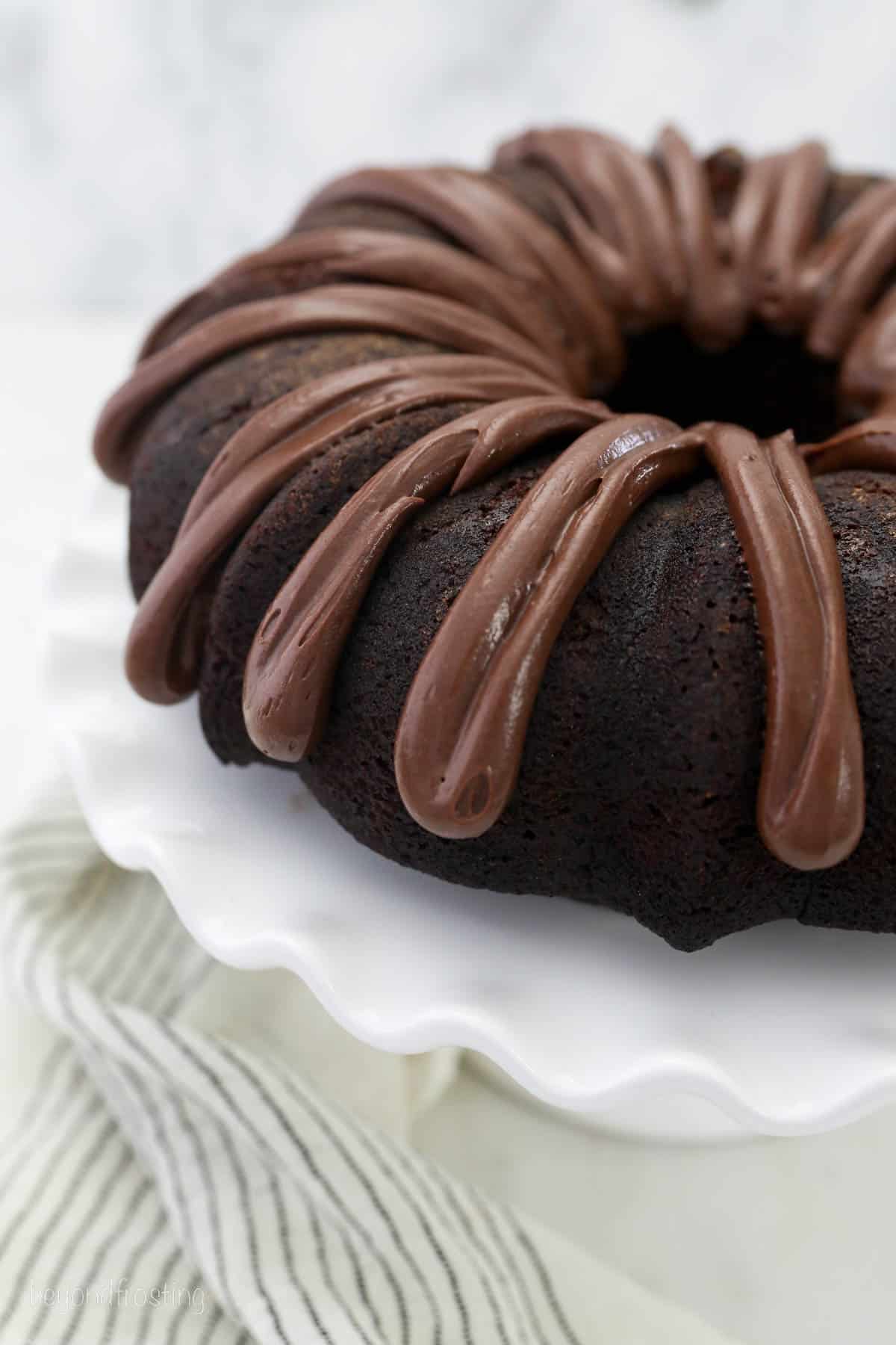 overhead of a whole chocolate bundt cake drizzled with chocolate frosting.