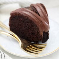 closeup of a slice of cake next to two gold forks.