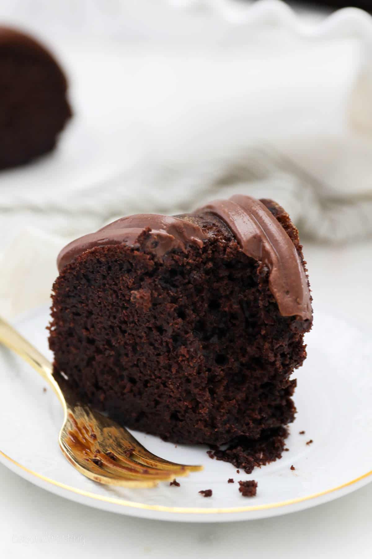 side view of a slice of chocolate bundt cake next to a gold fork.