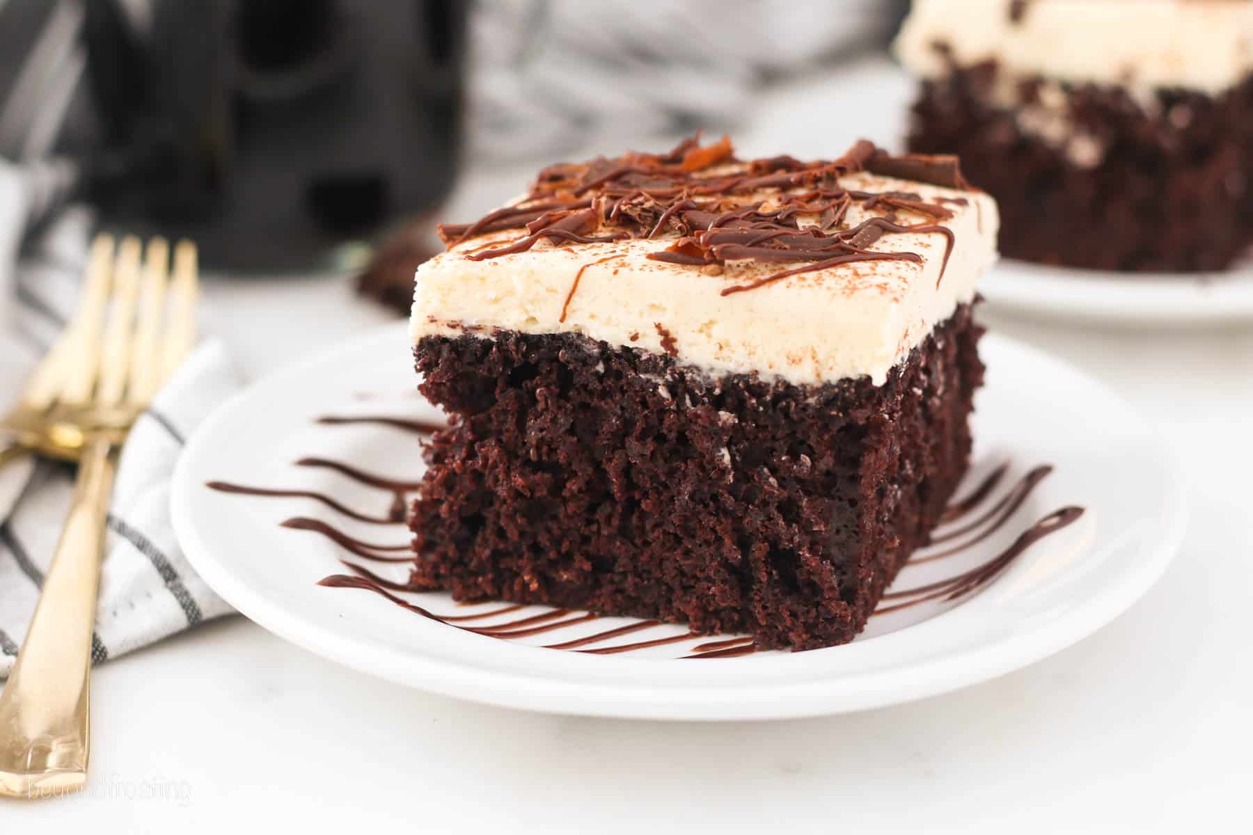 A slice of chocolate Guinness cake topped with Irish cream frosting and shaved chocolate on a plate.