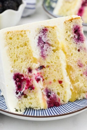 overhead of a slice of lemon blackberry cake with mascarpone frosting on a plate.