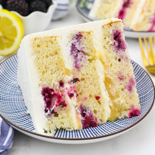 overhead of a slice of lemon blackberry cake with mascarpone frosting on a plate.