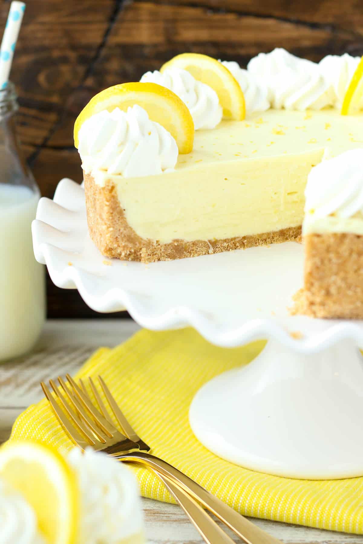 a lemon cream pie on a white cake stand with a slice cut out.