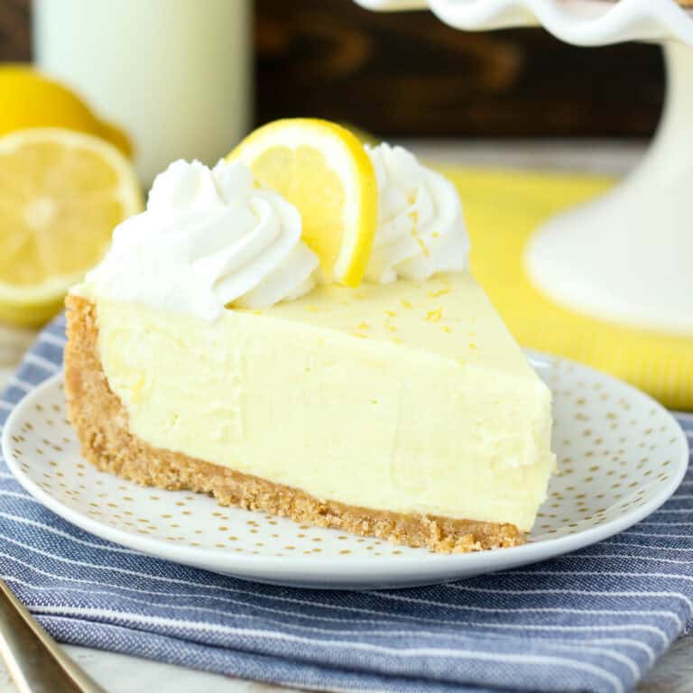 A slice of lemon cream pie topped with whip and a lemon slice.