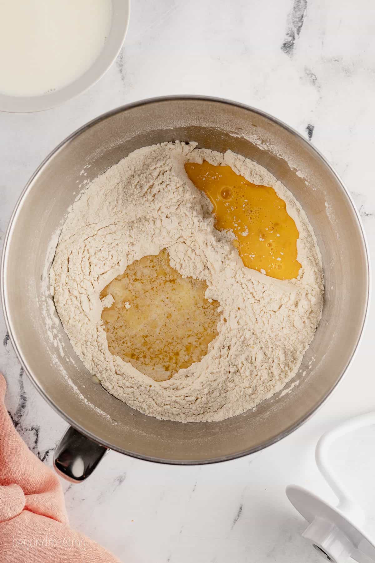 Melted butter and a beaten egg are added to a mixing bowl of dry ingredients.