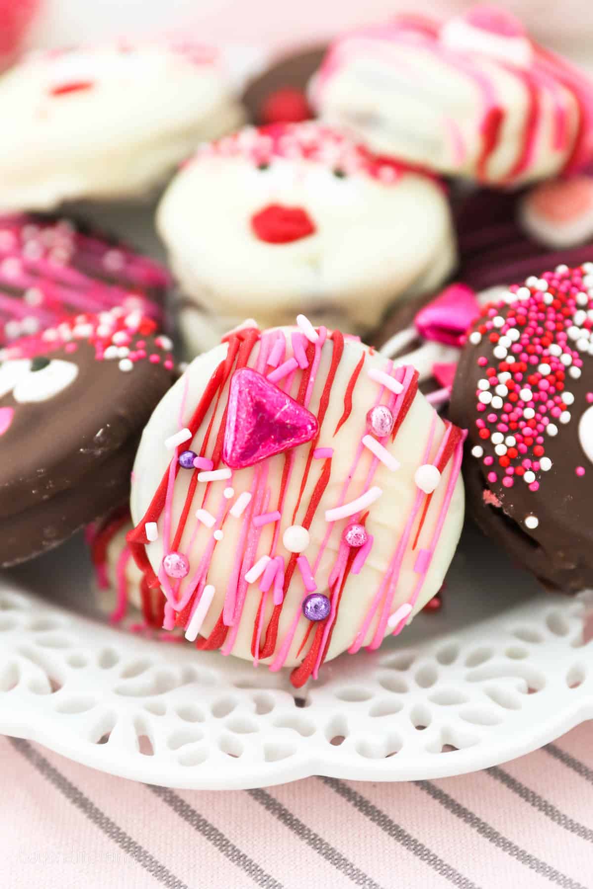 A white chocolate covered Oreos with pink and red drizzle decorated with sprinkles
