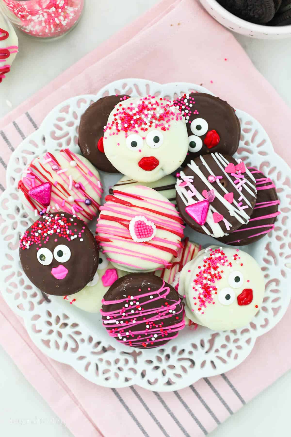 a plate of Chocolate dipped Oreos decorated for Valentine's Day on a white plate and pink napkin