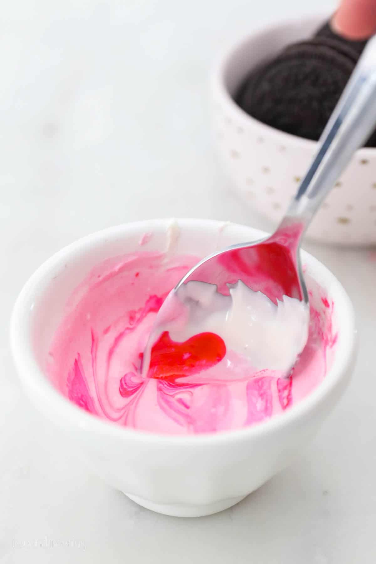 A spoon mixing pink color into white chocolate