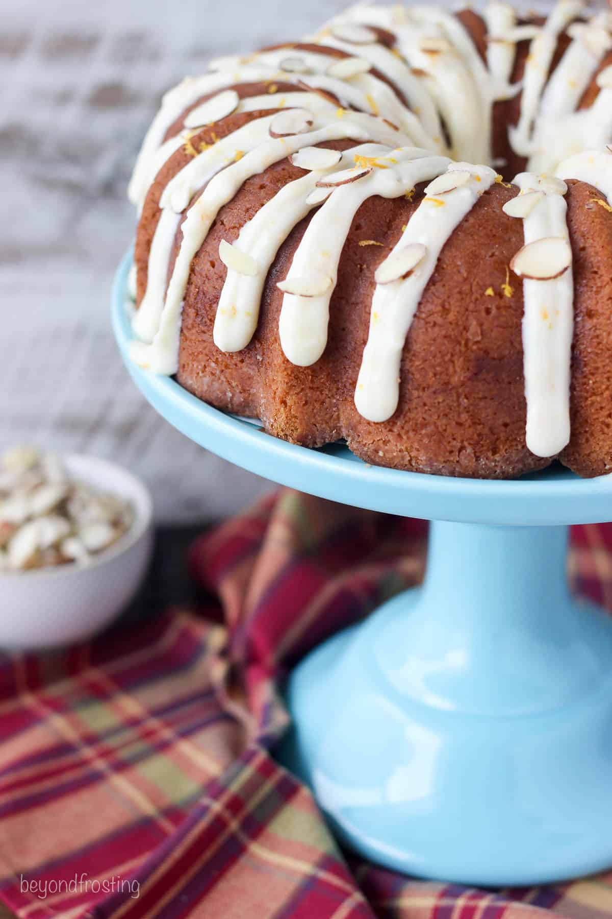a baked bundt cake on a blue cake stand topped with icing.
