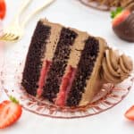 overhead of a thick slice of chocolate layer cake with strawberry filling on a plate.